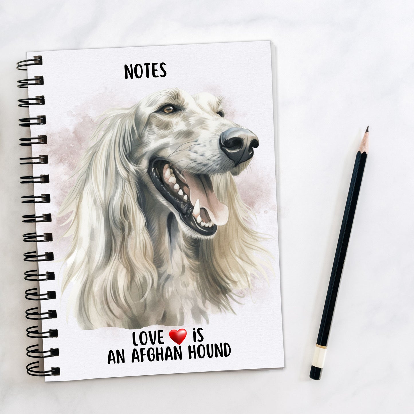White spiral bound notebook showing a head shot of a white Afghan Hound with flowing hair facing towards the right, mouth open and tongue out. A quote is written at the bottom. A black pencil is placed to the right hand side.