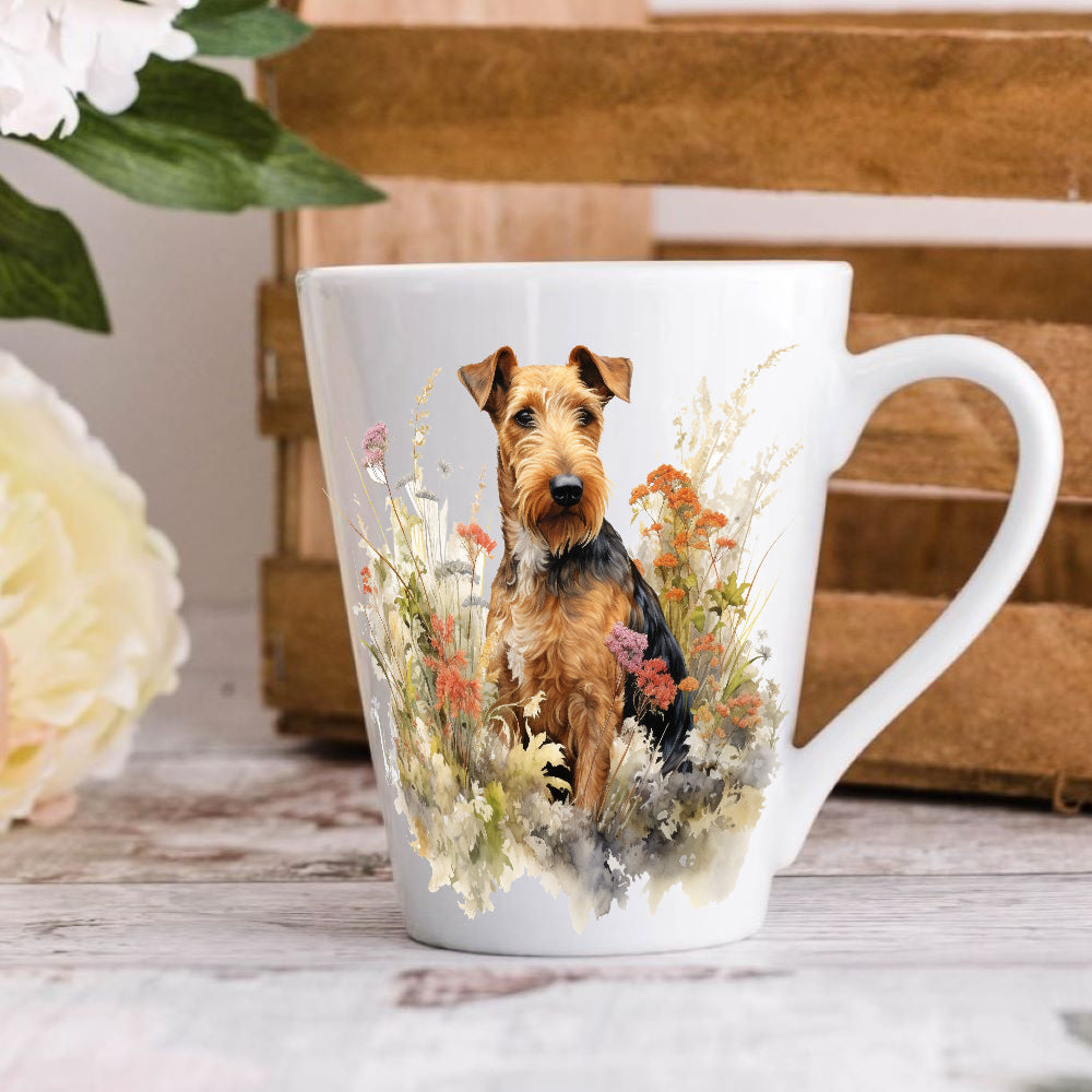 A 12oz ceramic latte mug with a printed image of an Airedale Terrier dog, surrounded by floral elements and a wooden crate in the background.