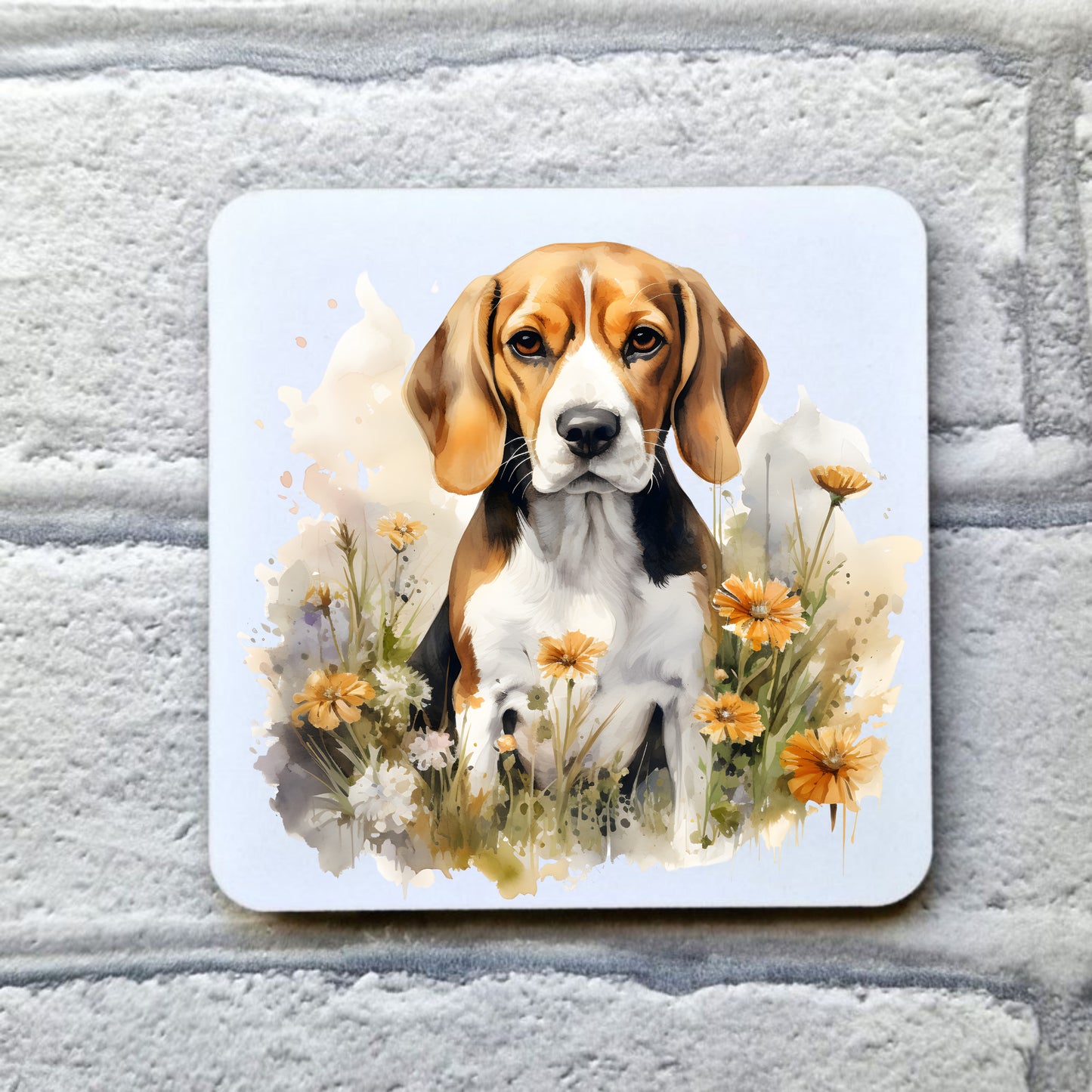 A Tri-coloured Beagle dog is sat among orange and white flowers looking forward with a soft expression. This image is set on a white coaster. The coaster is placed on a grey, brick effect surface.