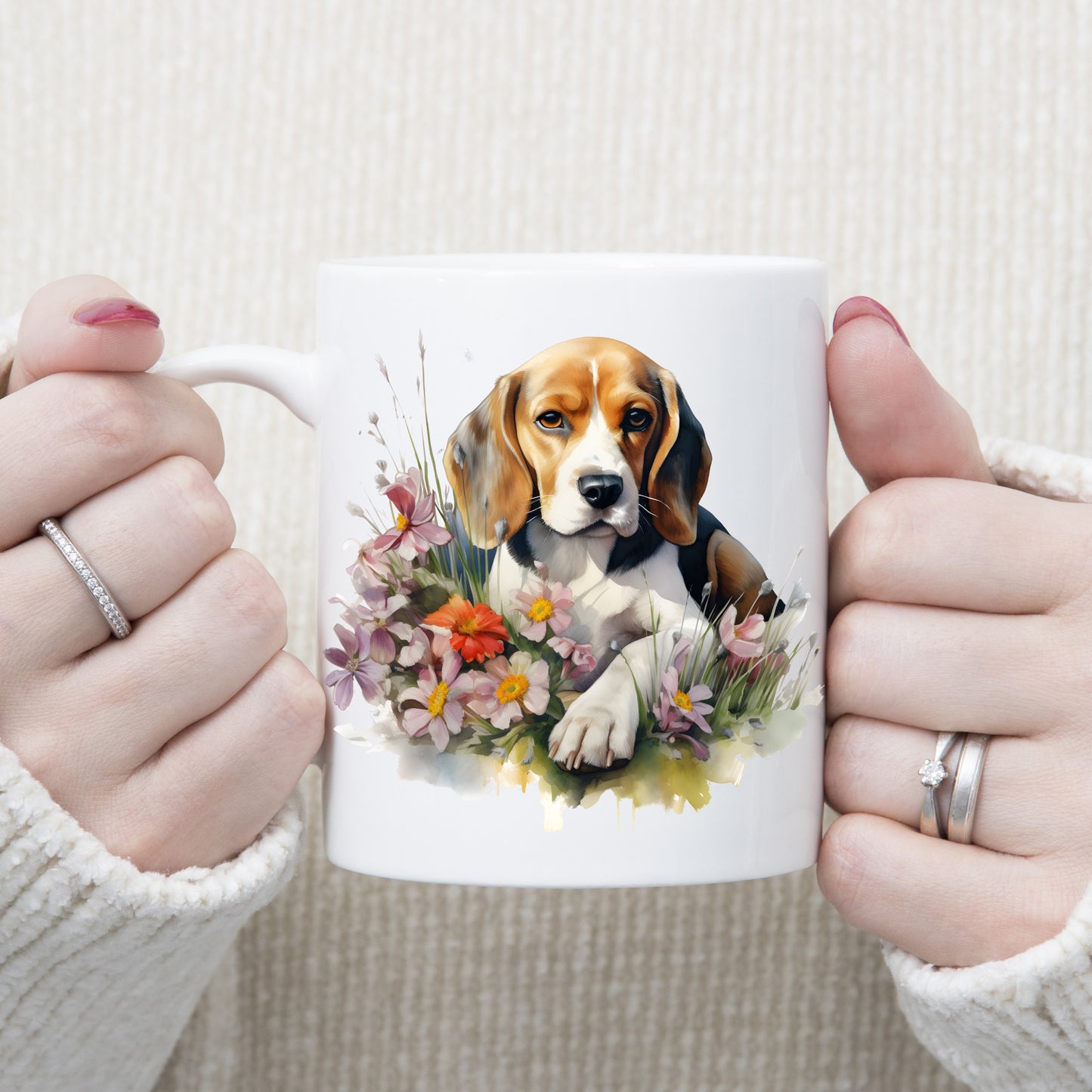 A cute Beagle dog is laid among purple and orange flowers on a white ceramic mug. A woman is holding the mug