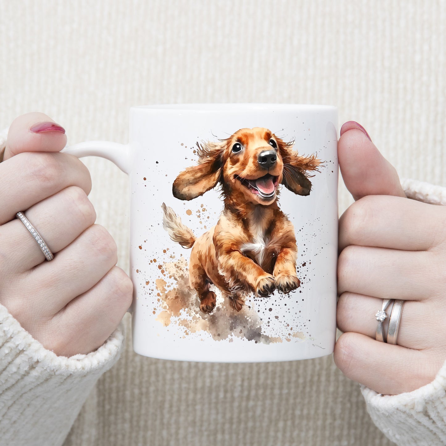 White ceramic mug with a happy Dachshund running and splashing. The mug is being held by a woman with both hands.