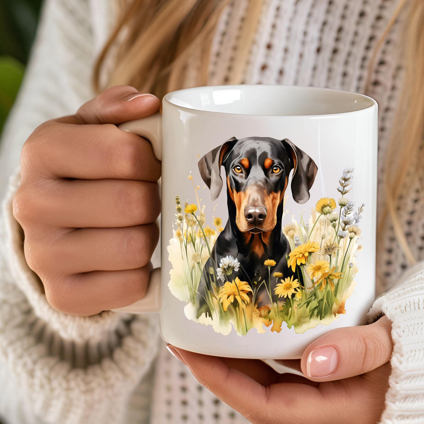 A 12oz white ceramic mug with a printed image of a black and tan Doberman facing forward and sitting among yellow flowers. A computer keyboard sits in the background. The mug is positioned on a wooden surface.