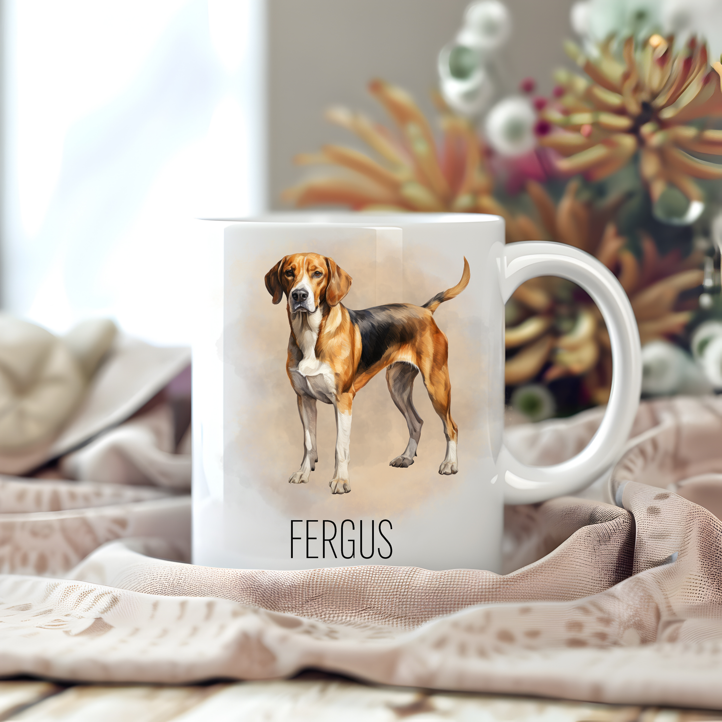 Personalised coffee mug featuring a beautiful Foxhound on a white ceramic mug which has been placed on a beige cloth. Stems of large flowers accessorizes the image.