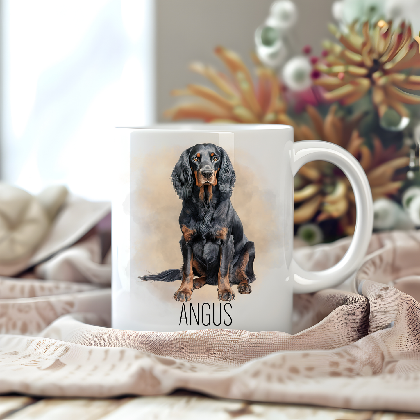 Personalised coffee mug featuring a seated Gordon Setter on a white ceramic mug which has been placed on a beige cloth. Stems of large flowers accessorizes the image.