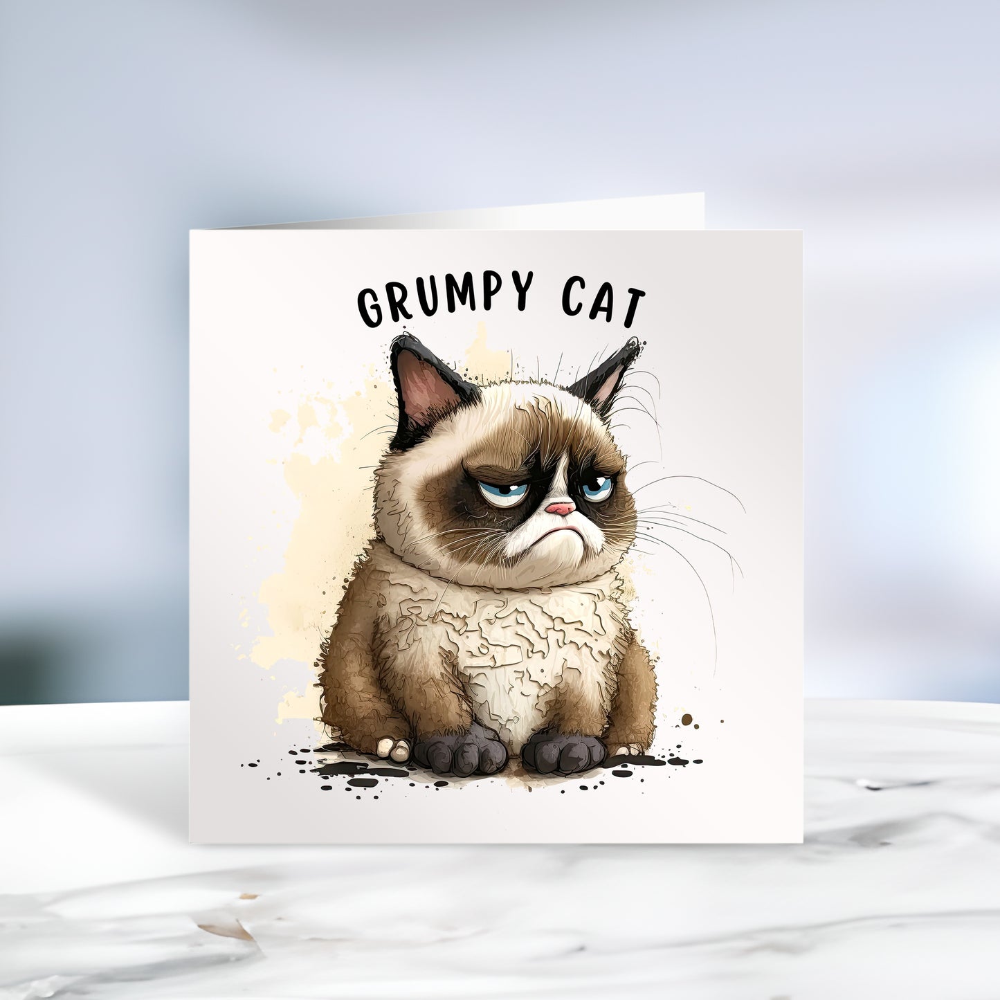 Grumpy cat on a white card with the words Grumpy Cat written at the top. The card is placed on grey marble surface.