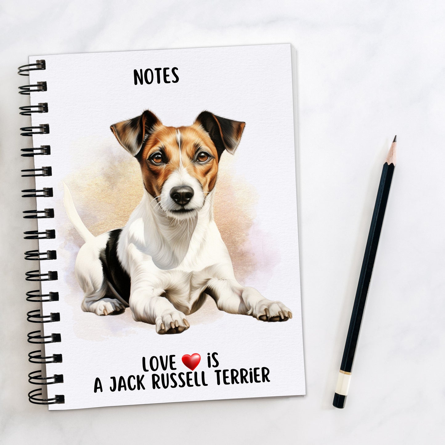 A5 white notepad with black spiral wire binding. A Jack Russell Terrier is laid facing foward on the front cover. A golden brown background decorates and a black pencil is placed to the right hand side. A quote with a red heart is placed at the bottom of the book.