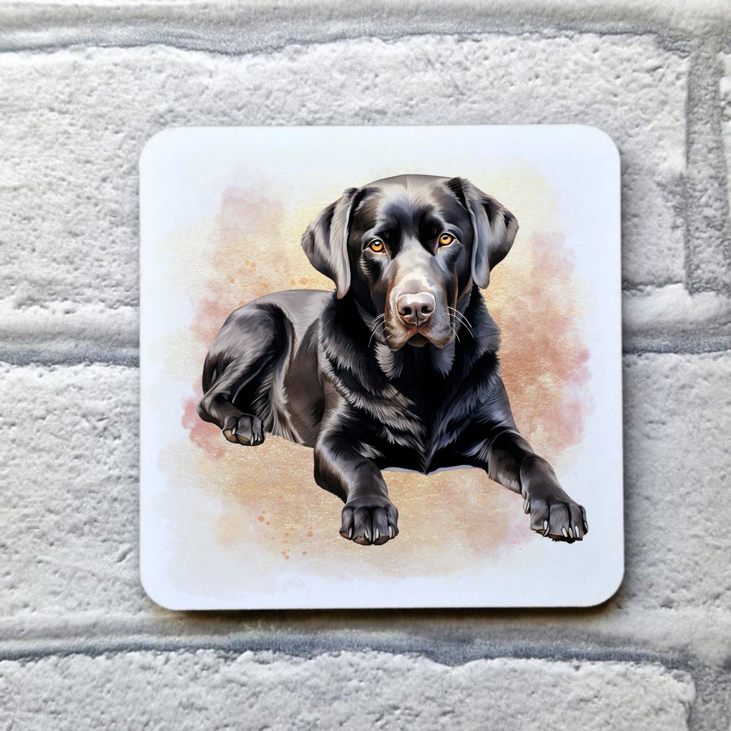 A Black Labrador is laid facing forward among a pink and gold misty background on a white drinks coaster. The coaster is placed on a grey, brick effect surface.
