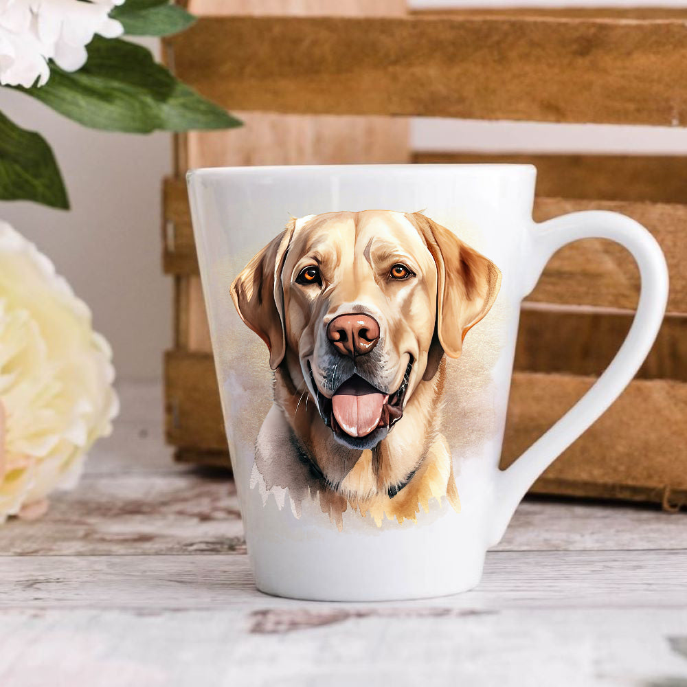 A latte coffee mug with a vibrant watercolor design of a yellow Labrador Retriever dog, placed on a wooden surface with flowers and a book in the background.