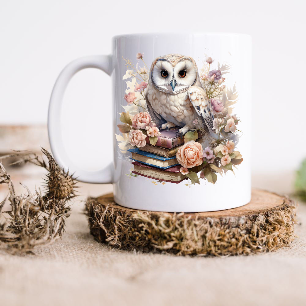 Barn Owl sat on books surrounded by flowers on a white ceramic mug which is placed on a rustic wooden disc.