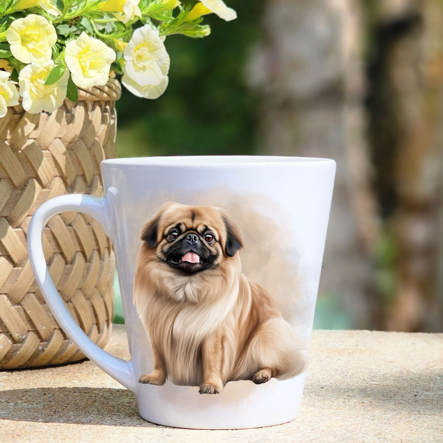 A white ceramic latte mug featuring a seated Pekingese dog in a beige mist background. A basket containing yellow flowers sits to the left-hand side.