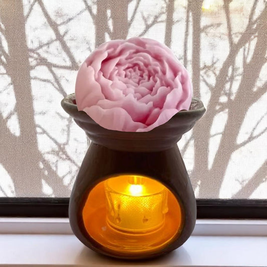Aroma lamp with a pink flower wax melt on top, emitting a warm glow.