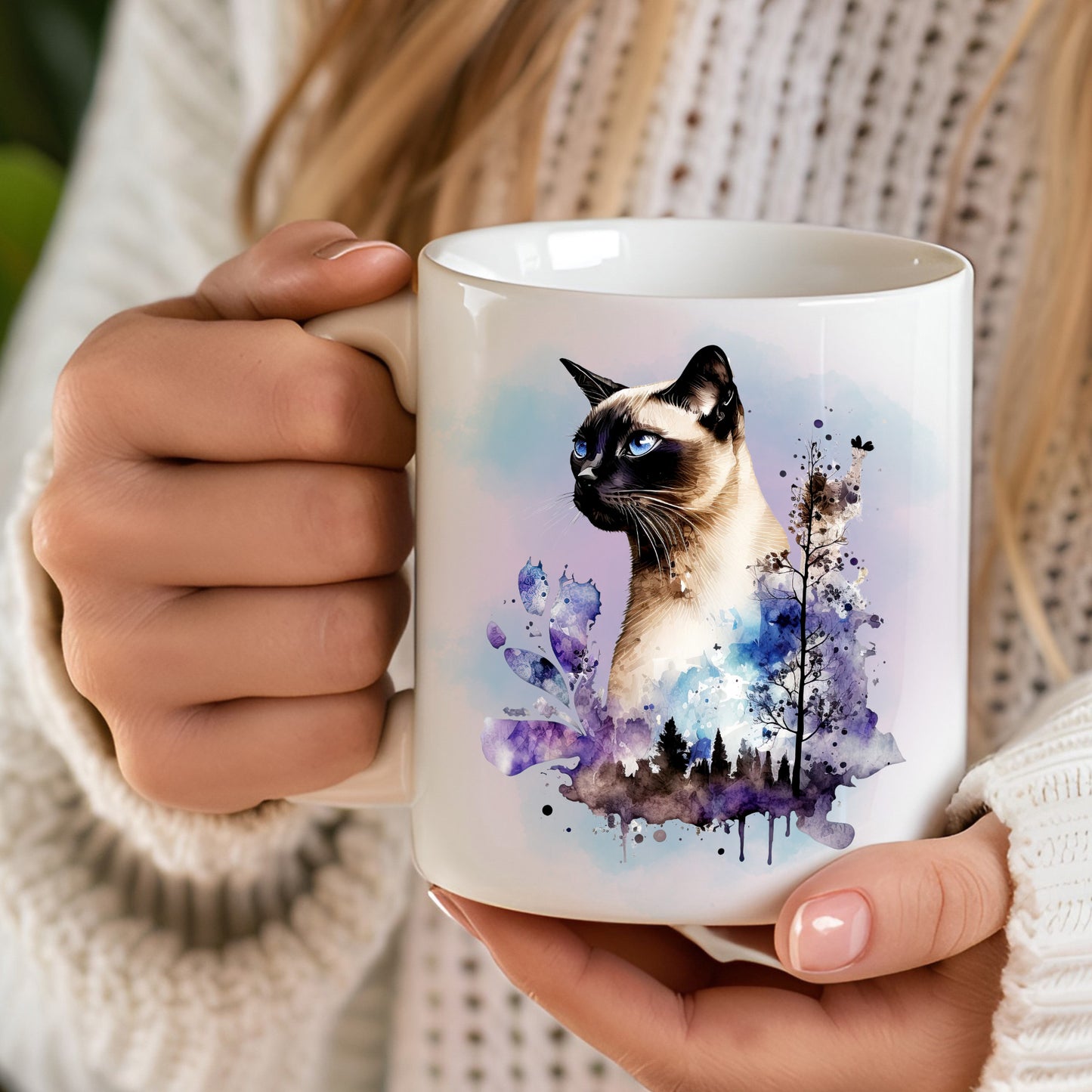 woman holding a white ceramic mug featuring a siamese cat with a blue and purple background. Splash detailing and trees.