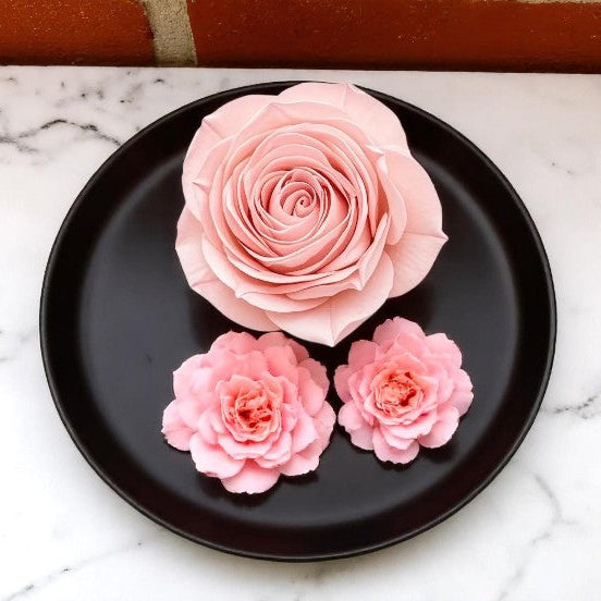 Pink wax melt roses on a black plate with a marble background