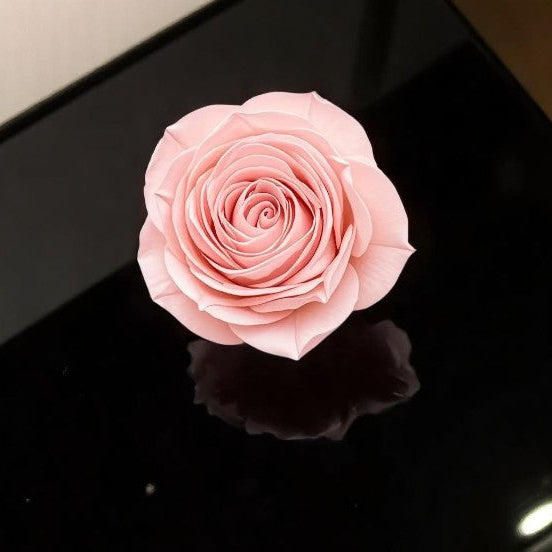 Pink wax melt rose on a reflective black surface