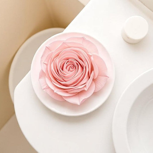 Pink wax melt rose on a white plate with a beige background
