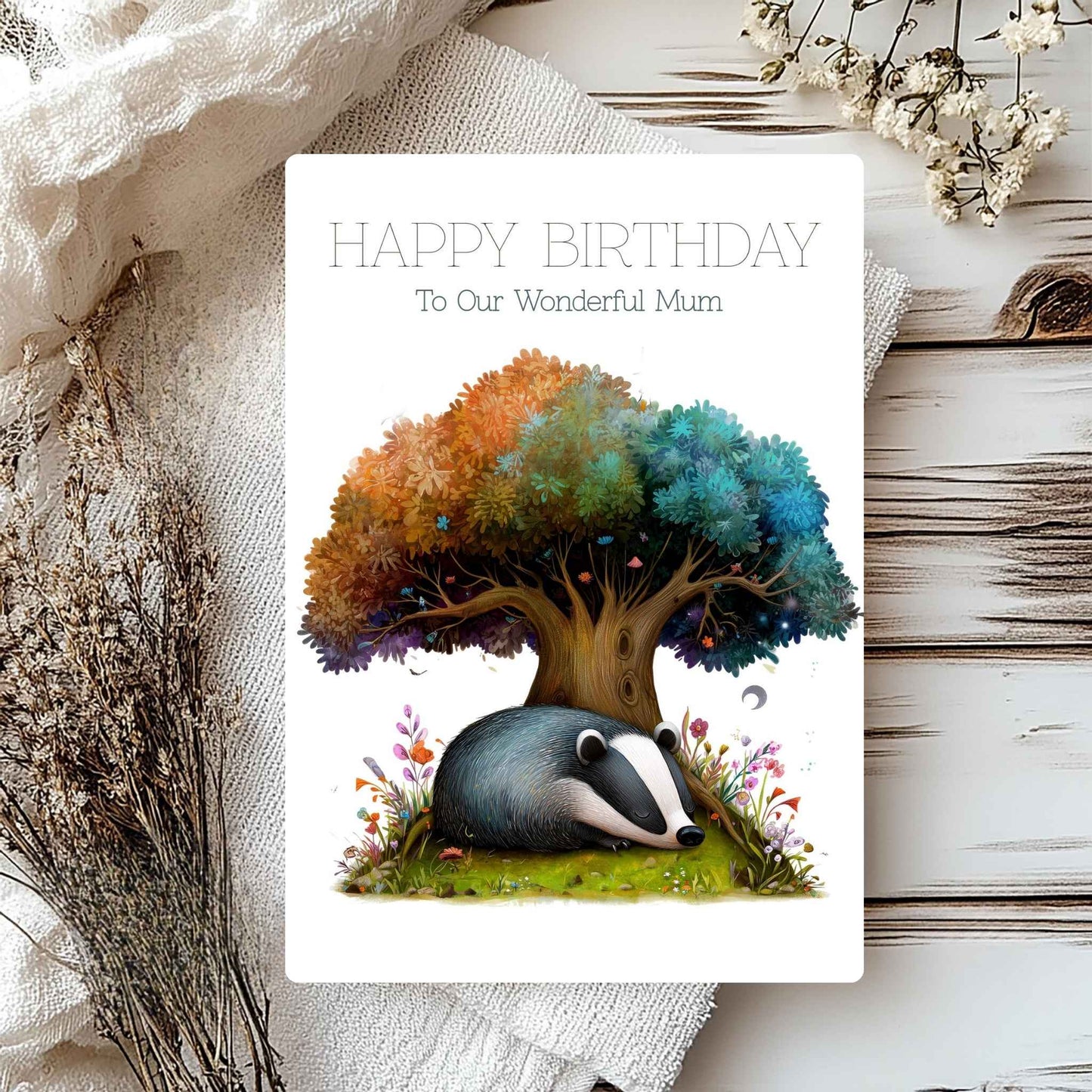 Greeting card with a badger and tree design, text 'Happy Birthday To Our Wonderful Mum', on a textured surface with flowers.