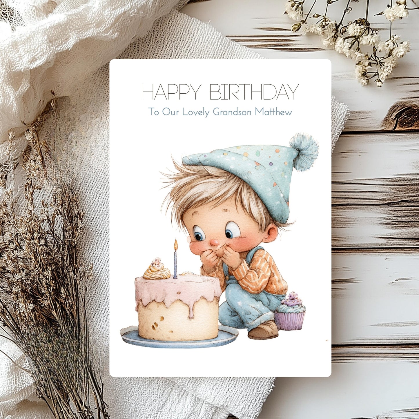 Birthday card with a child illustration and cake, surrounded by decorative elements on a wooden surface.