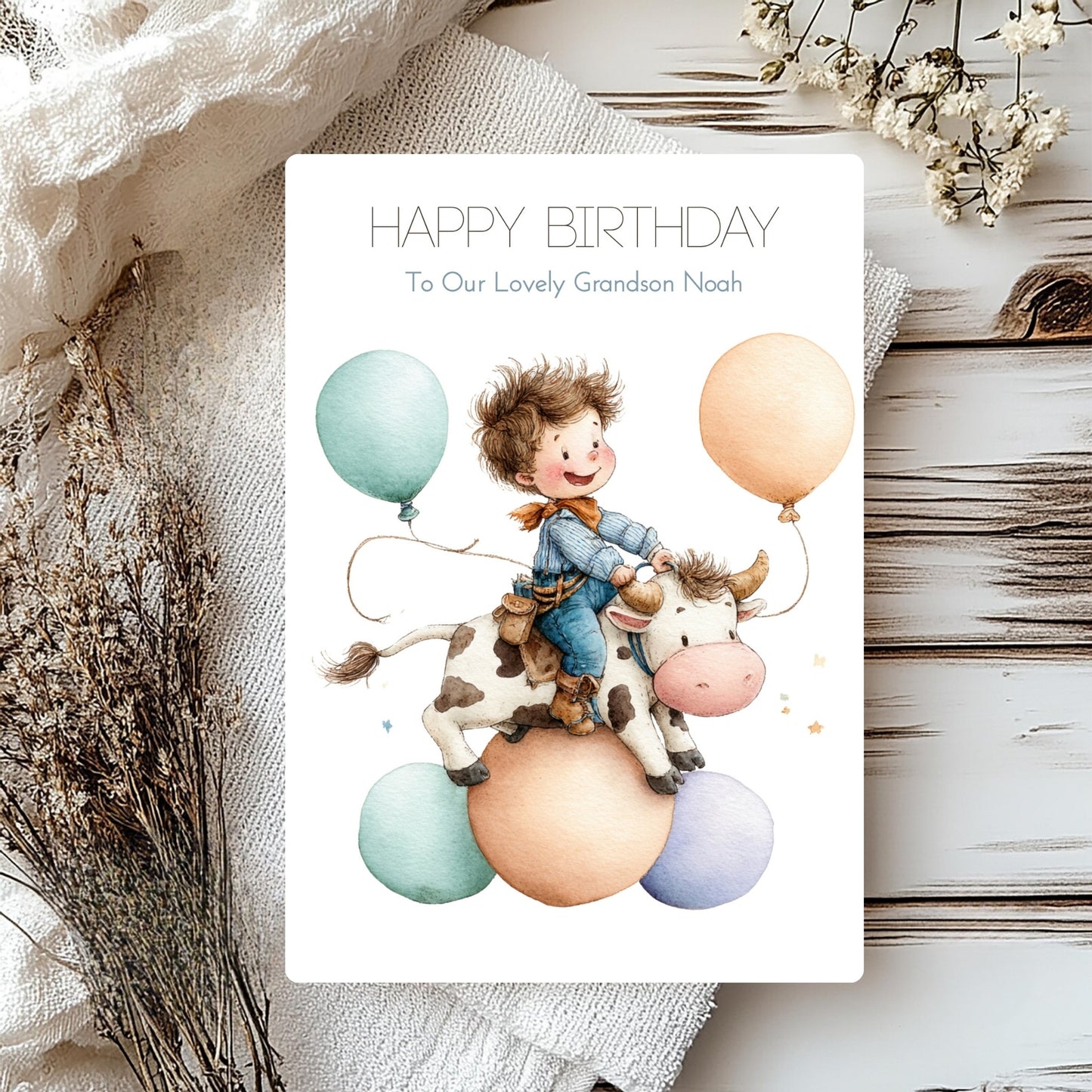 Birthday card with illustration of a child riding a cow with balloons on a wooden surface.