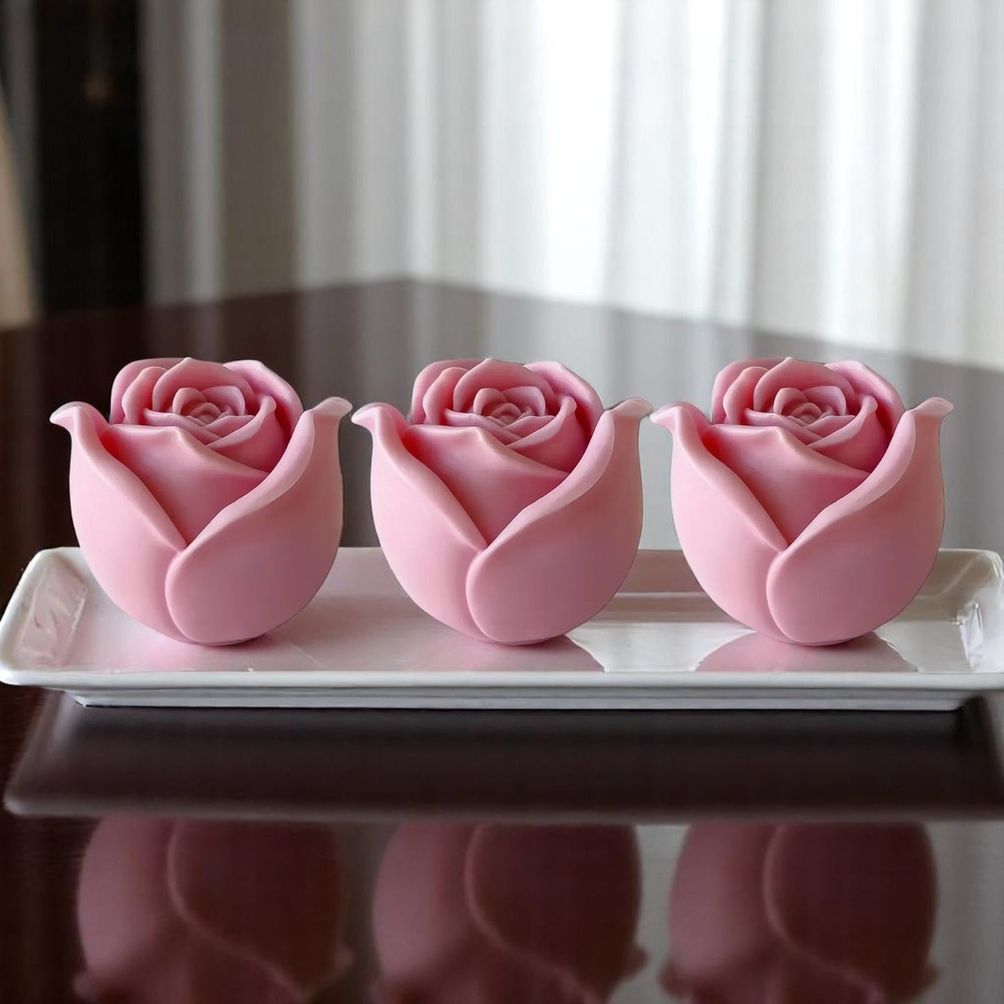 Three pink rose-shaped wax melts on a white plate.