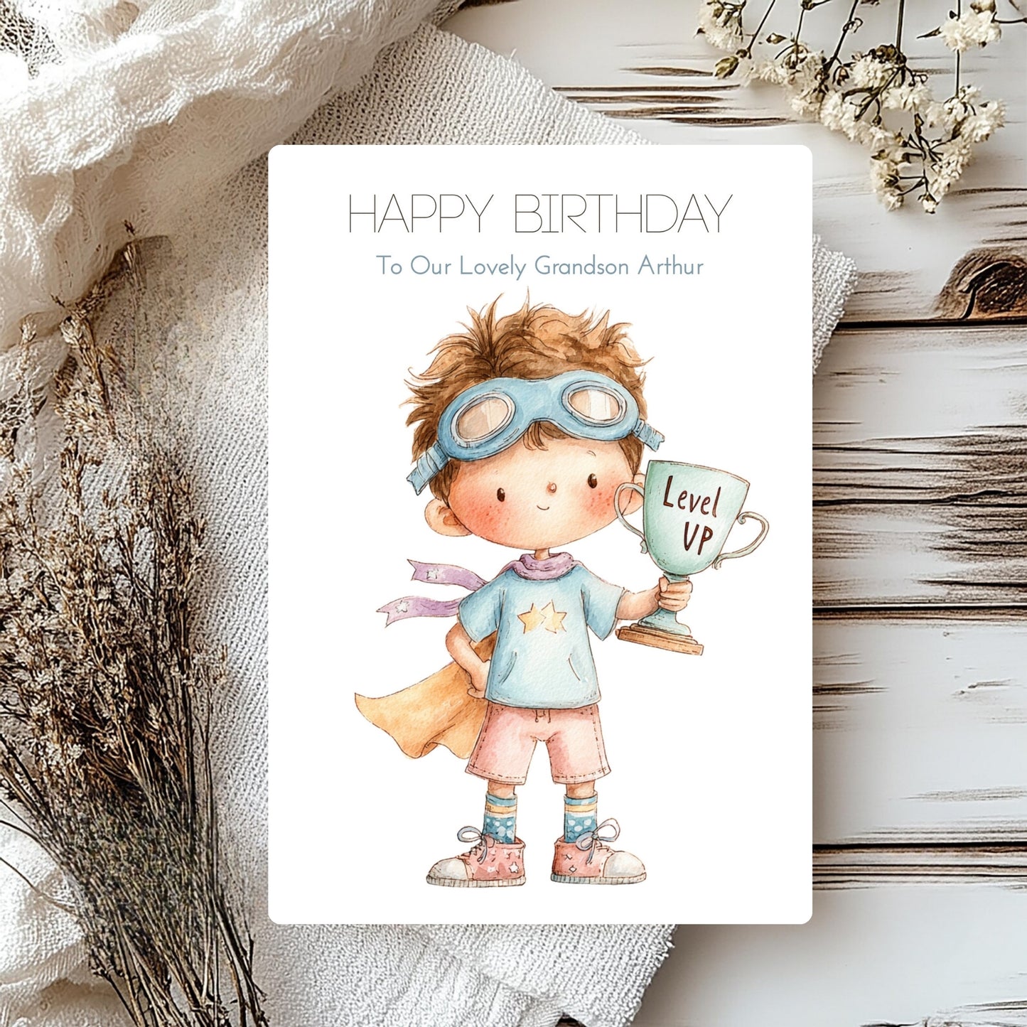 Birthday card with a child holding a 'Level Up' cup on a textured surface with flowers.