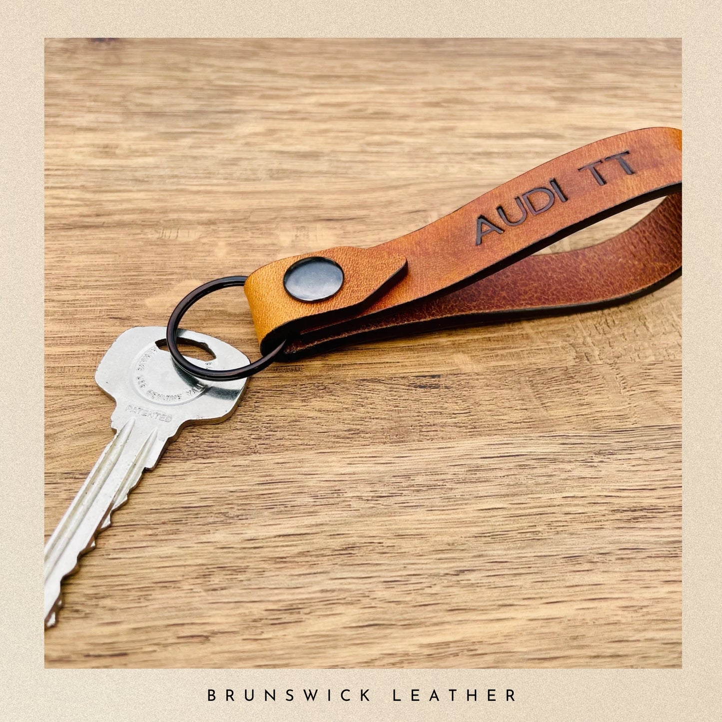 Leather keychain with 'Audi' branding on a wooden surface, featuring the brand 'Brunswick Leather'.