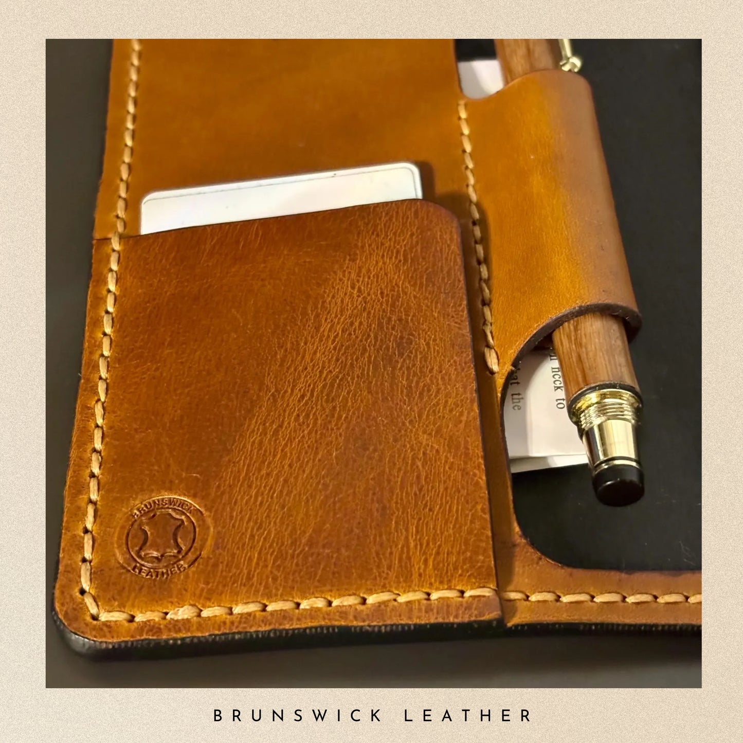 Brown leather case with a pen and card holder, featuring the Brunswick Leather logo.