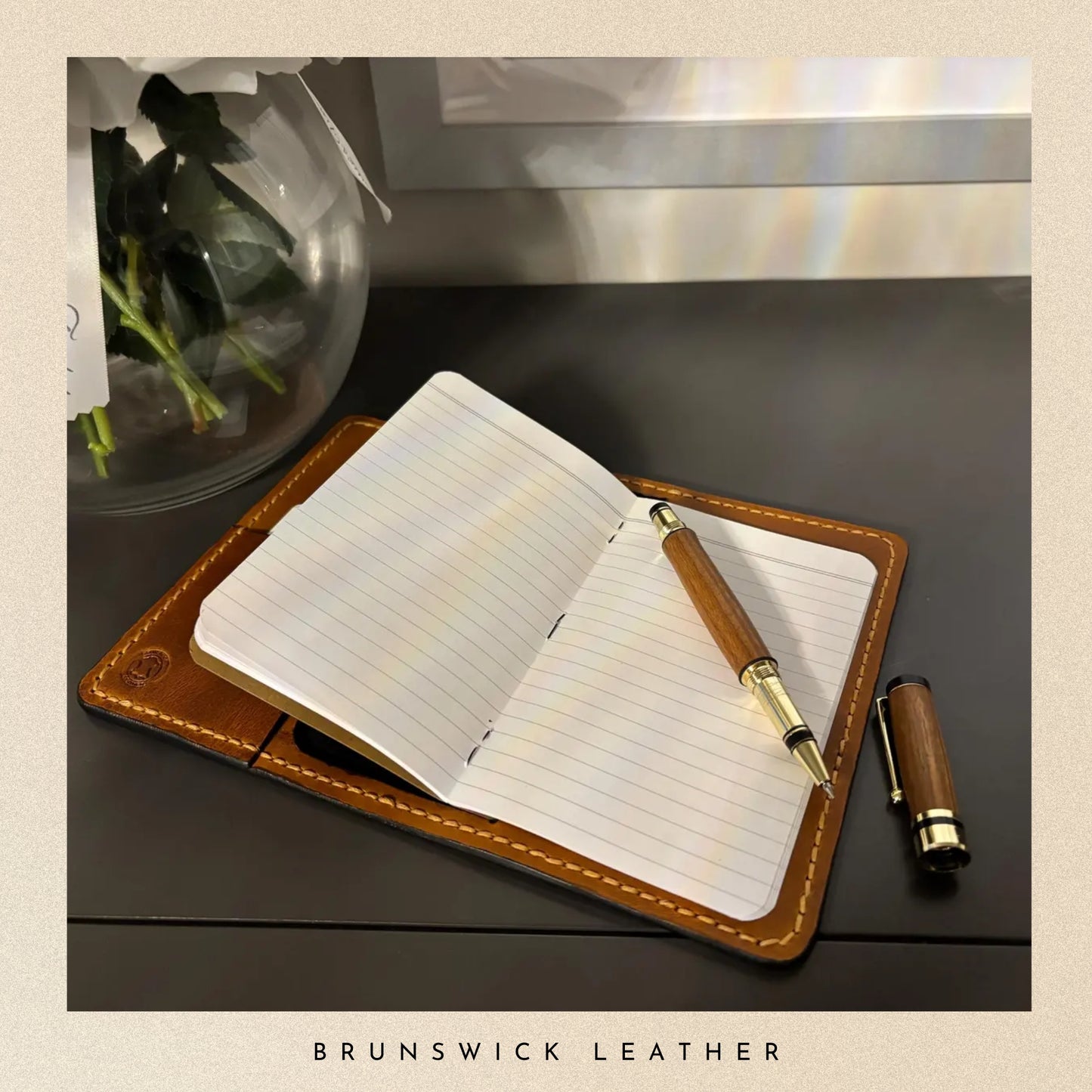 Open notebook with leather cover and pen on a dark surface, featuring 'Brunswick Leather' branding.