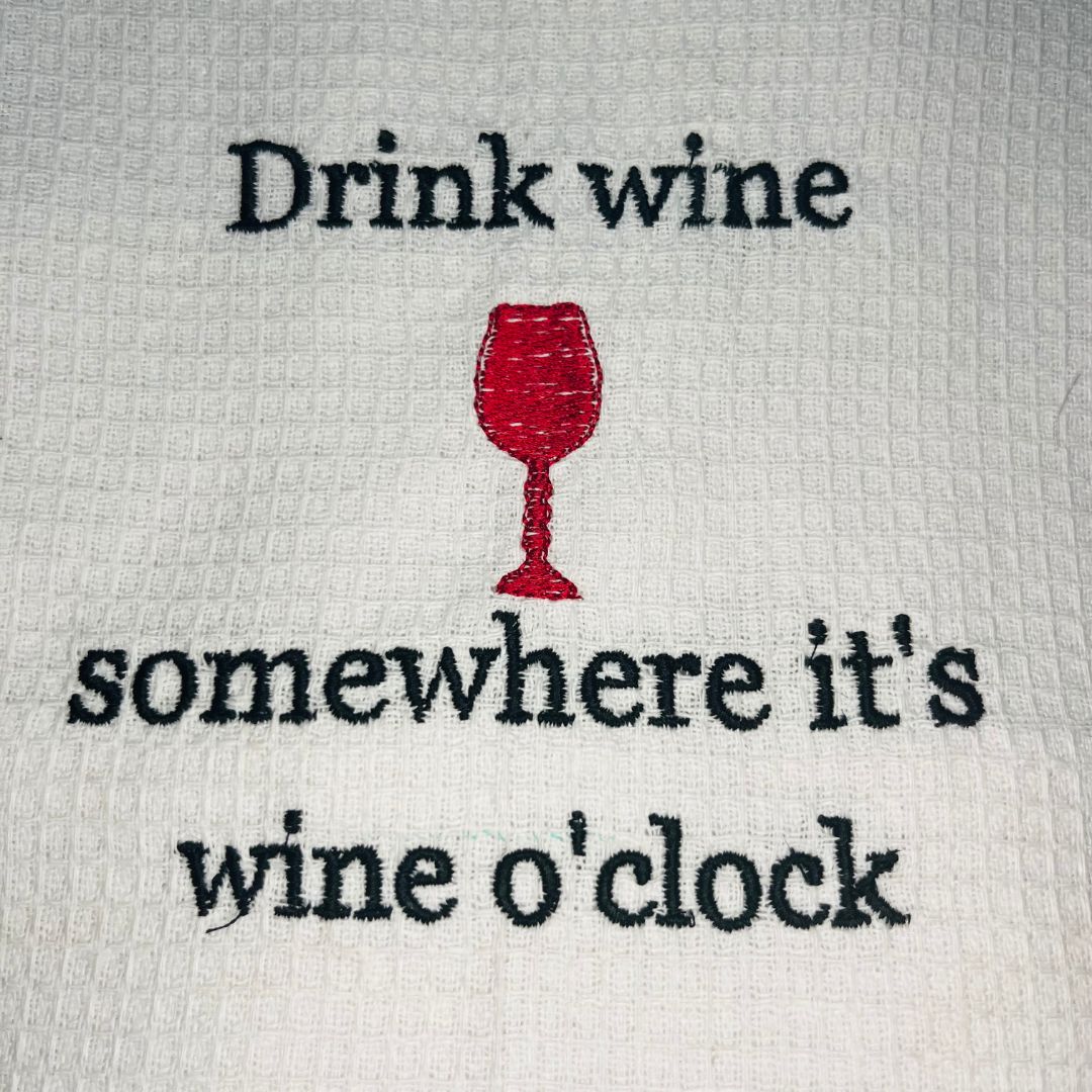 Close up of waffle tea towel design for wine lovers with the slogan "drink wine, somewhere it's wine o'clock"