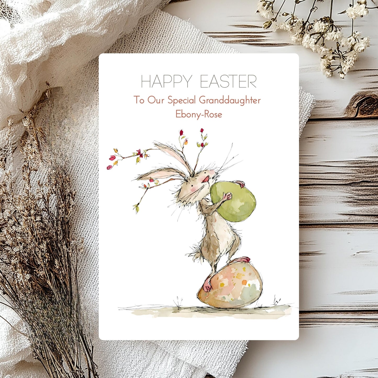 Easter card with a bunny holding an egg on a textured surface with flowers.