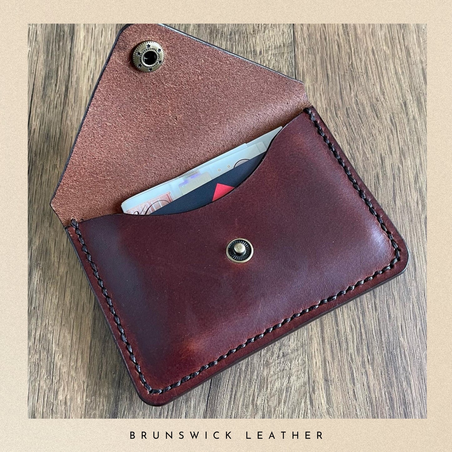 Brown leather wallet with visible stitching on a wooden surface, branded 'Brunswick Leather'.
