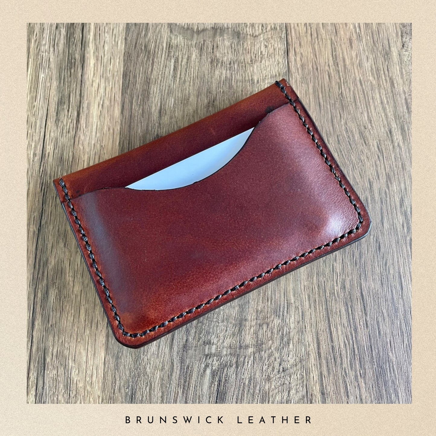 Brown leather cardholder on a wooden surface with 'Brunswick Leather' branding.