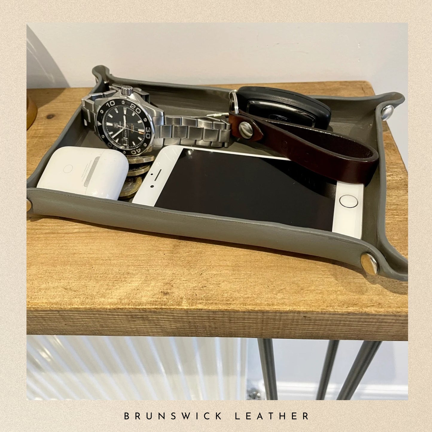 Tray with phone, watch, and other items on a wooden surface with 'Brunswick Leather' branding.