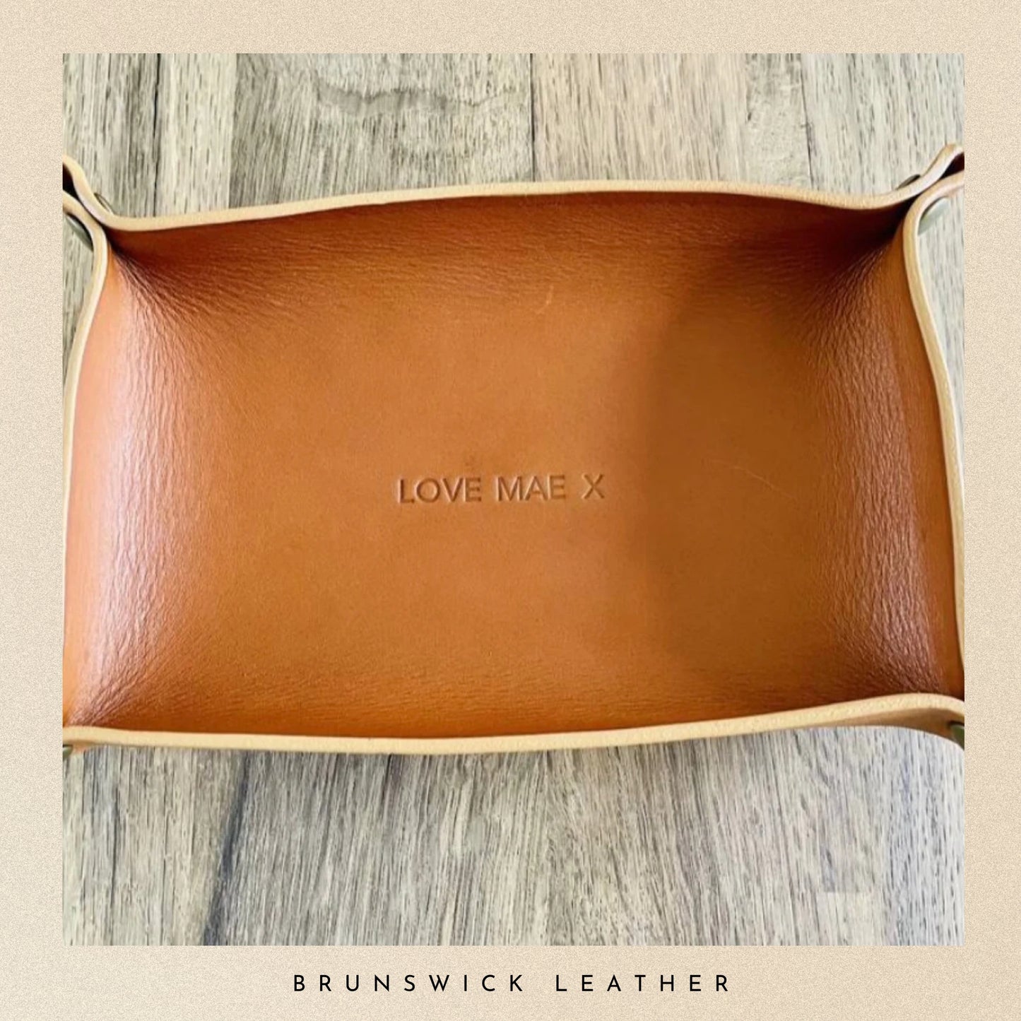 Brown leather tray with 'LOVE MAE X' branding on a wooden surface, branded 'Brunswick Leather'.