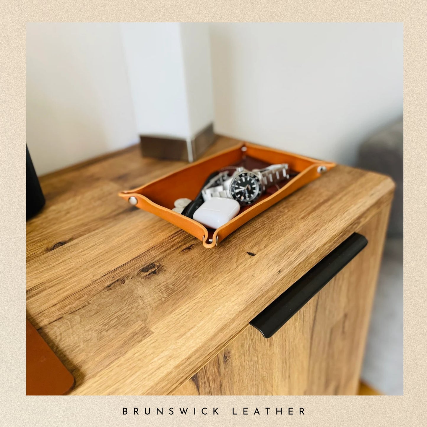 Orange leather tray on a wooden surface with 'Brunswick Leather' branding.