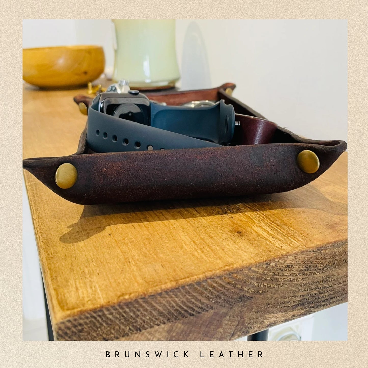 Leather tray with a watch on a wooden surface, branded 'Brunswick Leather'.