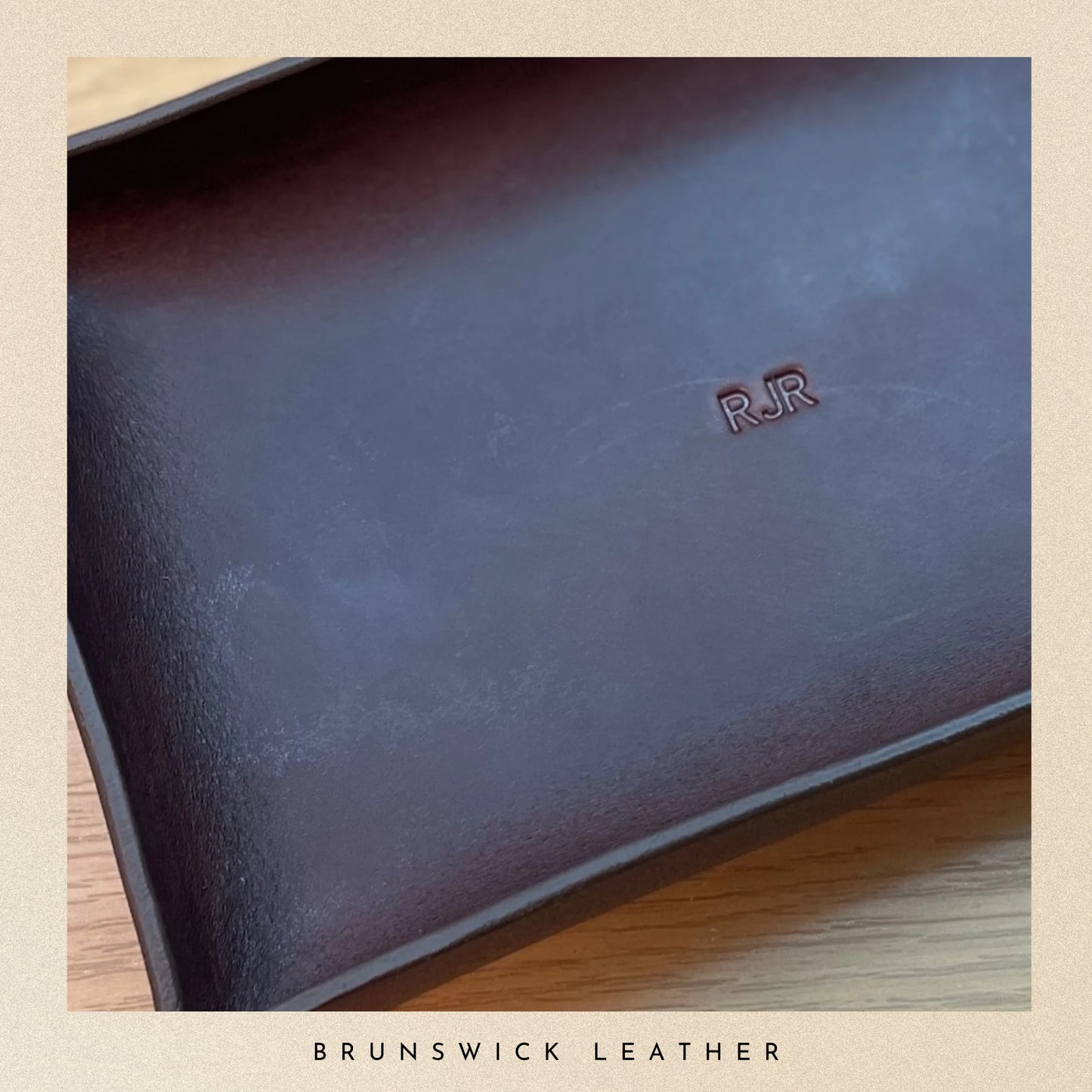 Dark leather tray with 'RJR' branding on a wooden surface, branded 'Brunswick Leather'.