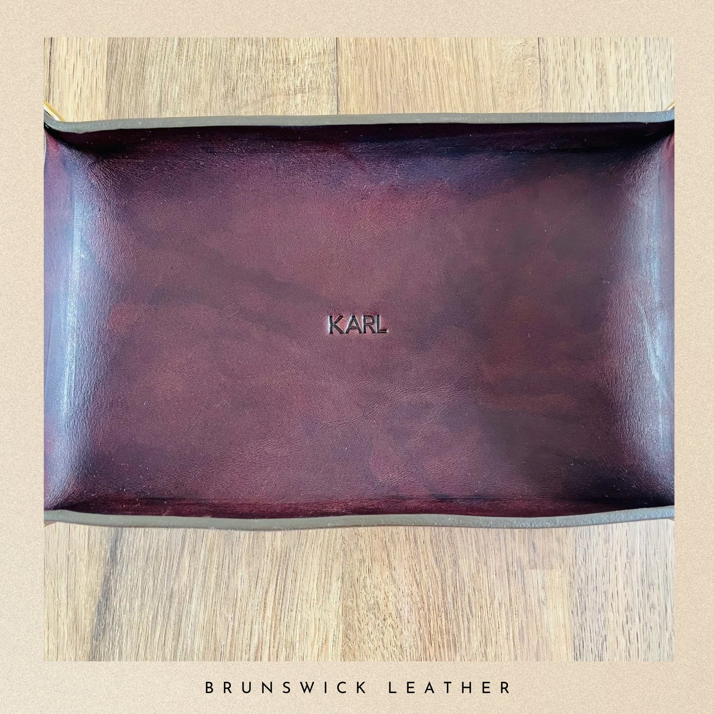 Brown leather pouch with 'Karl' branding on a wooden surface, branded 'Brunswick Leather'.