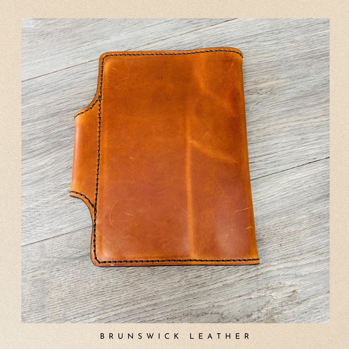 Brown leather wallet on a light wooden surface with 'Brunswick Leather' branding.