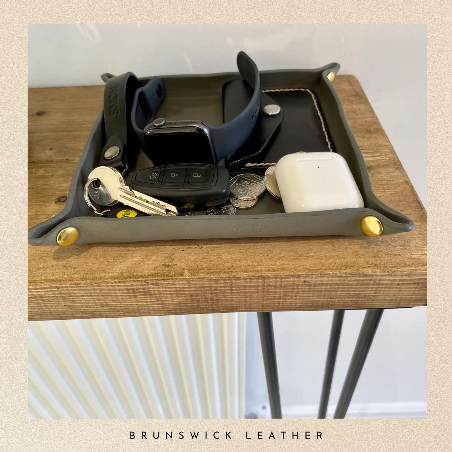 Tray with various items on a wooden surface, featuring the brand 'Brunswick Leather'.