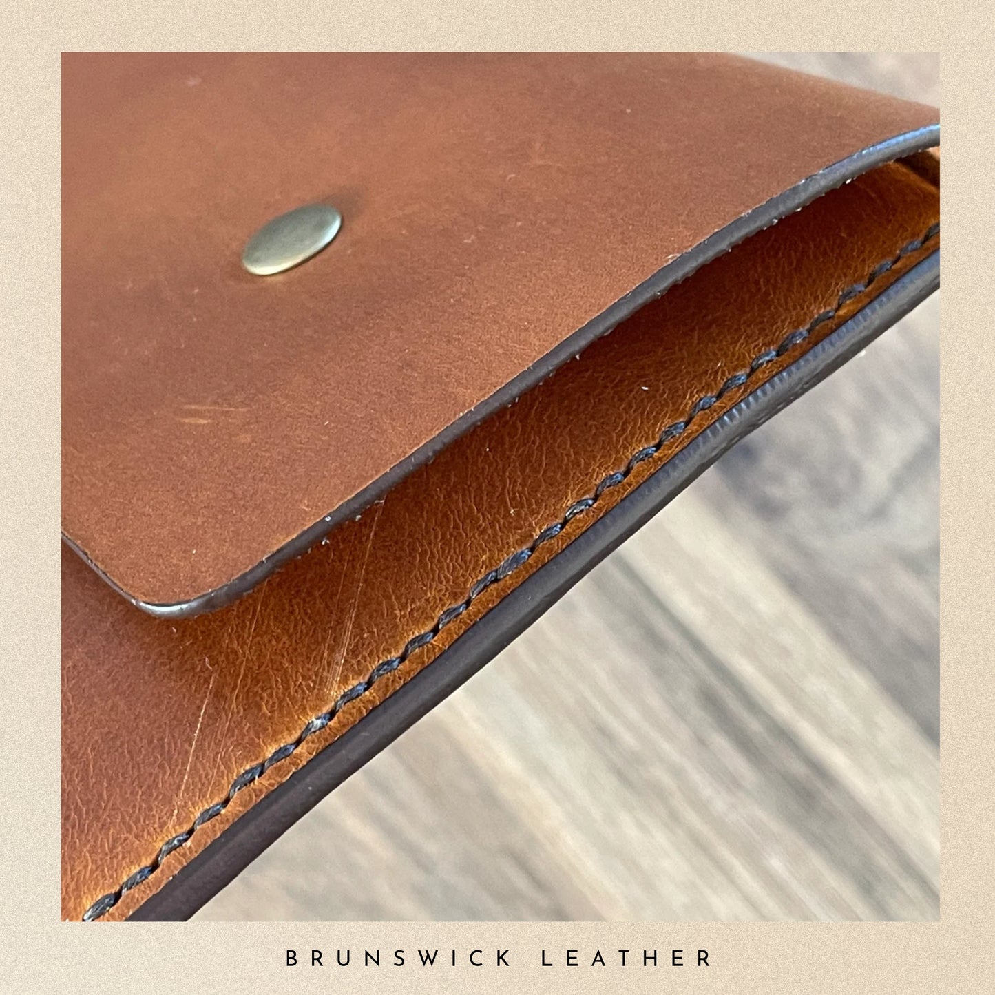 Close-up of a brown leather product with visible stitching and a metal tag, branded 'Brunswick Leather'.