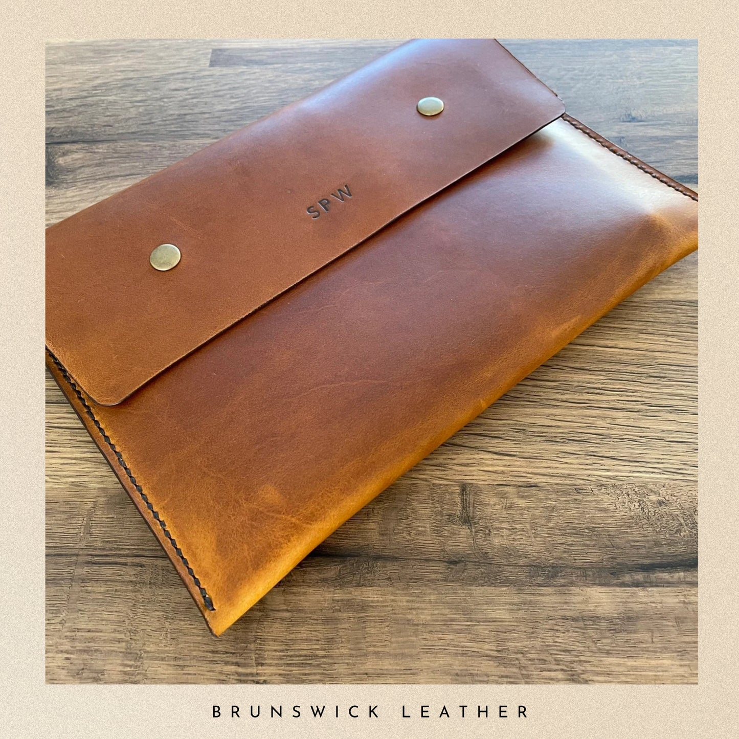 Brown leather pouch with 'SPW' initials on a wooden surface, branded 'Brunswick Leather'.