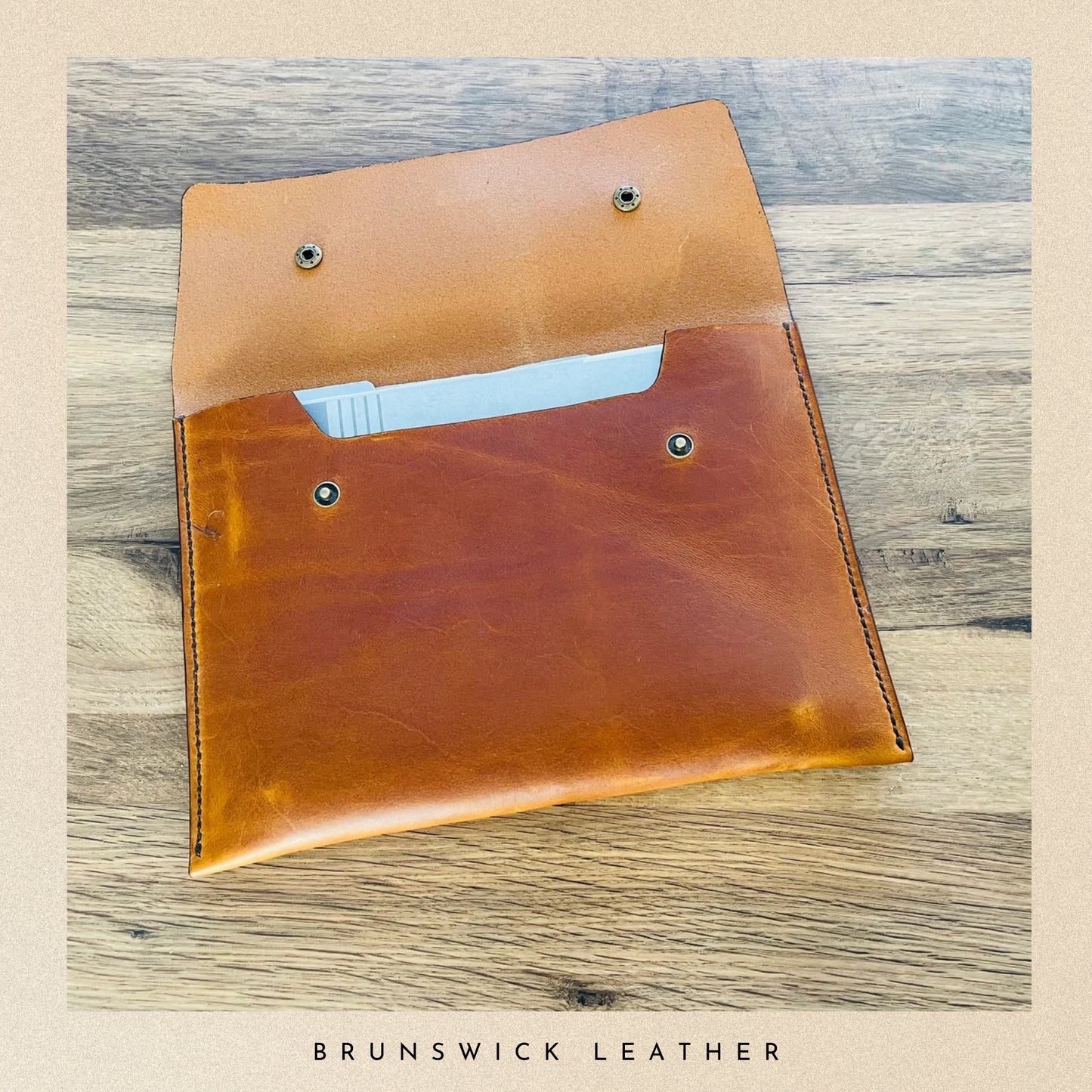 Brown leather pouch on a wooden surface with 'Brunswick Leather' branding.