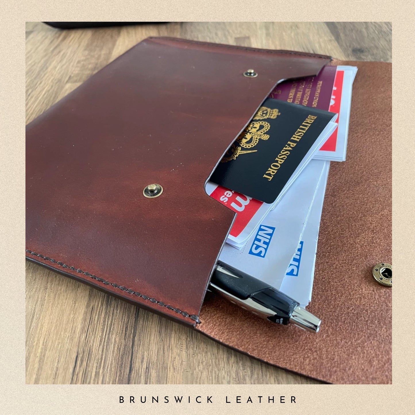 Brown leather wallet with passport and cards on a wooden surface, branded 'Brunswick Leather'.
