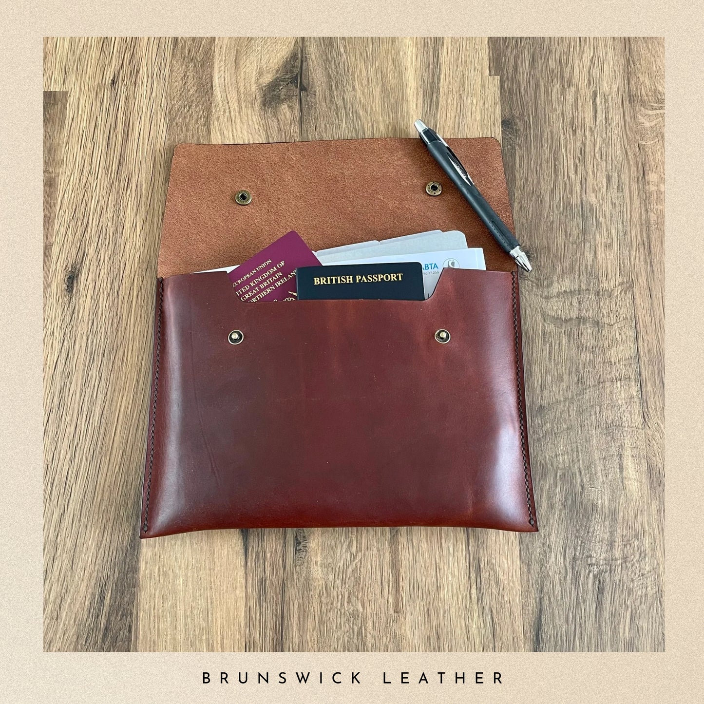 Brown leather wallet with passport and cards on a wooden surface, branded 'Brunswick Leather'.