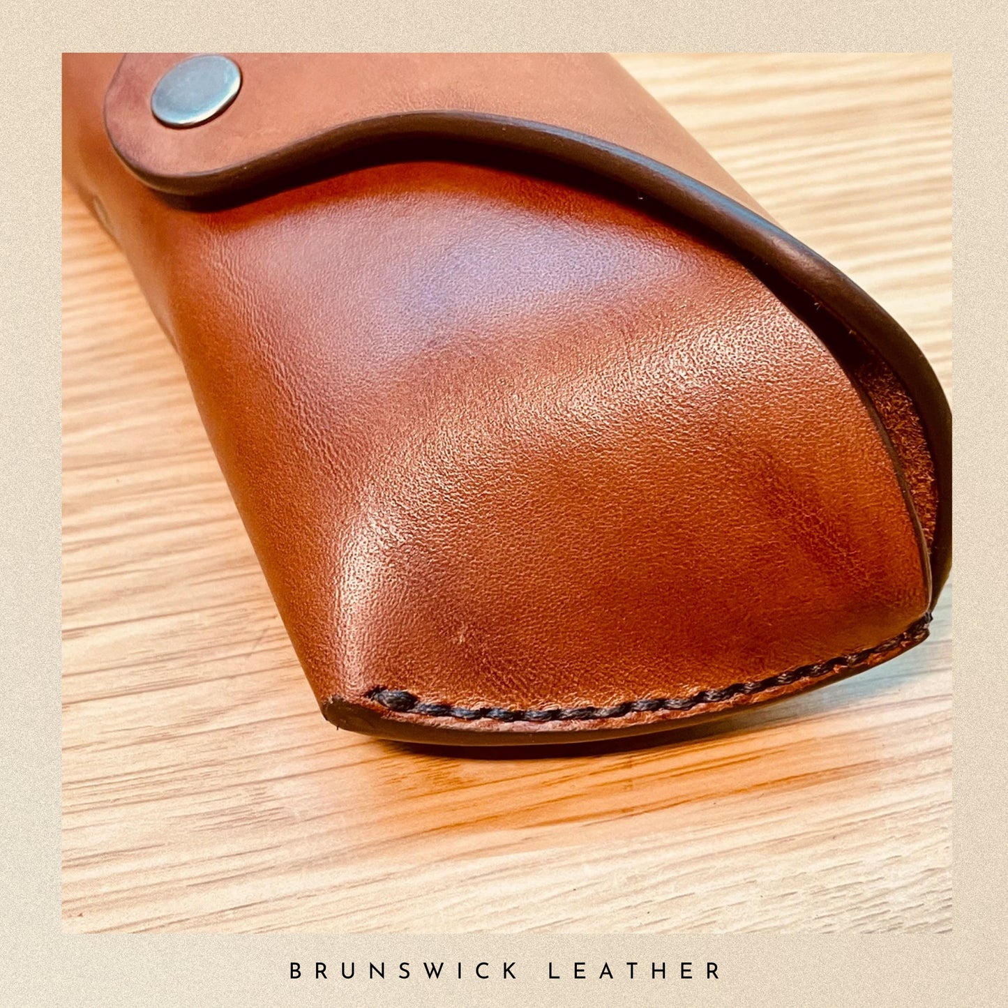 Brown leather case on a wooden surface with 'Brunswick Leather' branding.