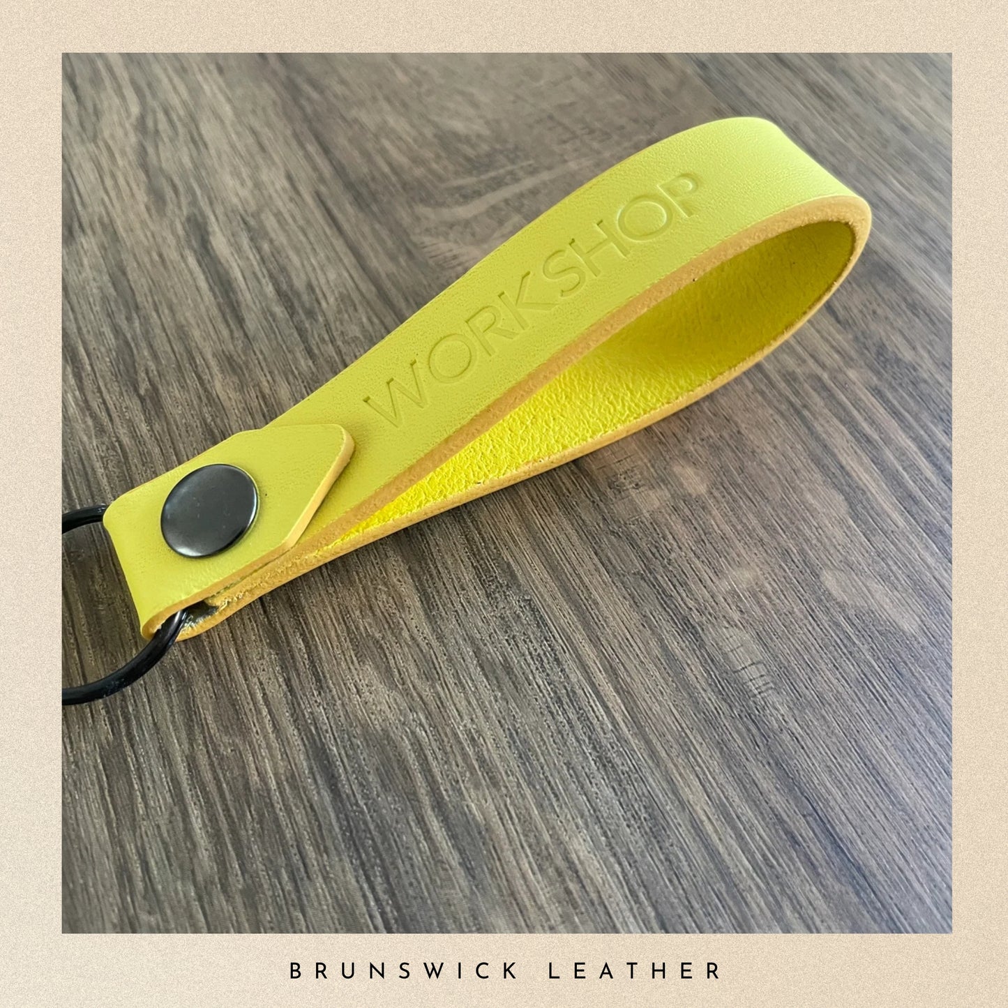 Yellow leather strap with 'Workshop' branding on a wooden surface, featuring Brunswick Leather.
