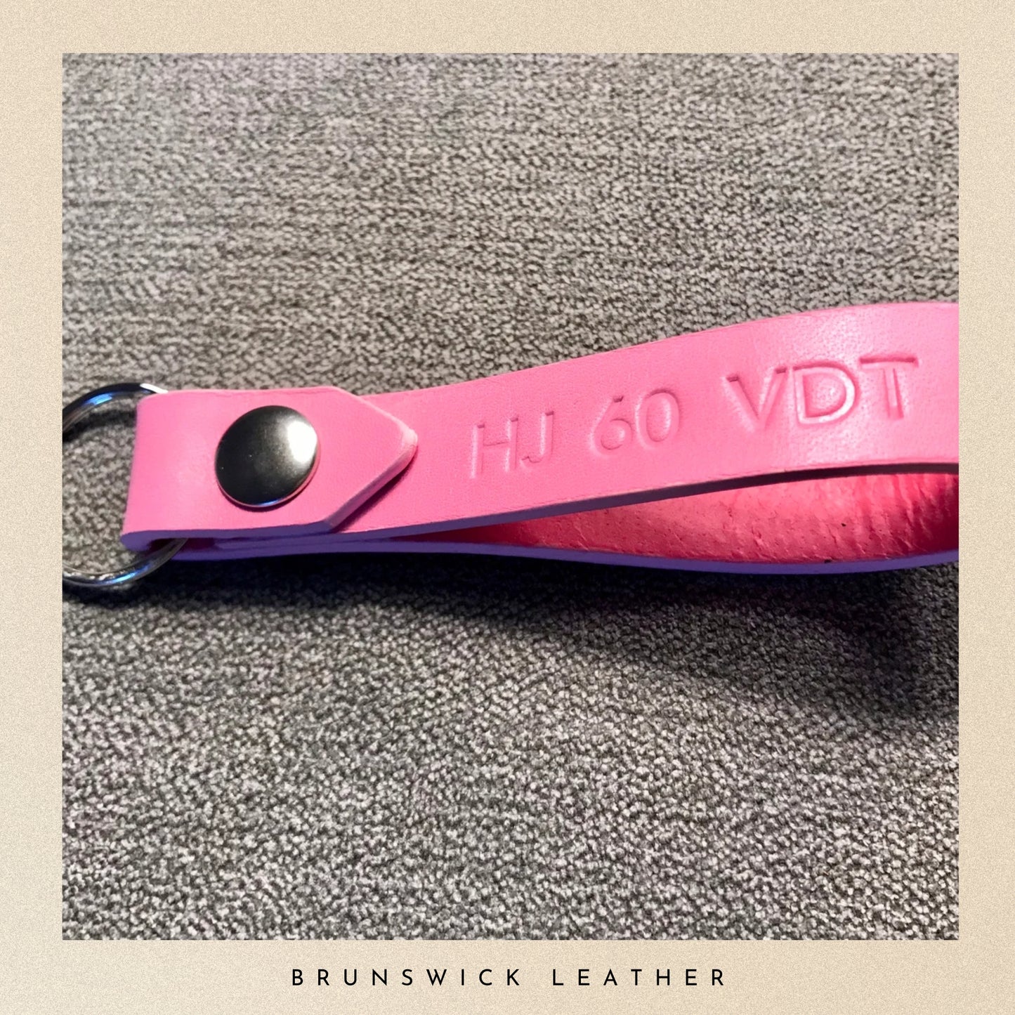 Pink leather keychain with metal clasp on a textured surface, branded 'Brunswick Leather'.