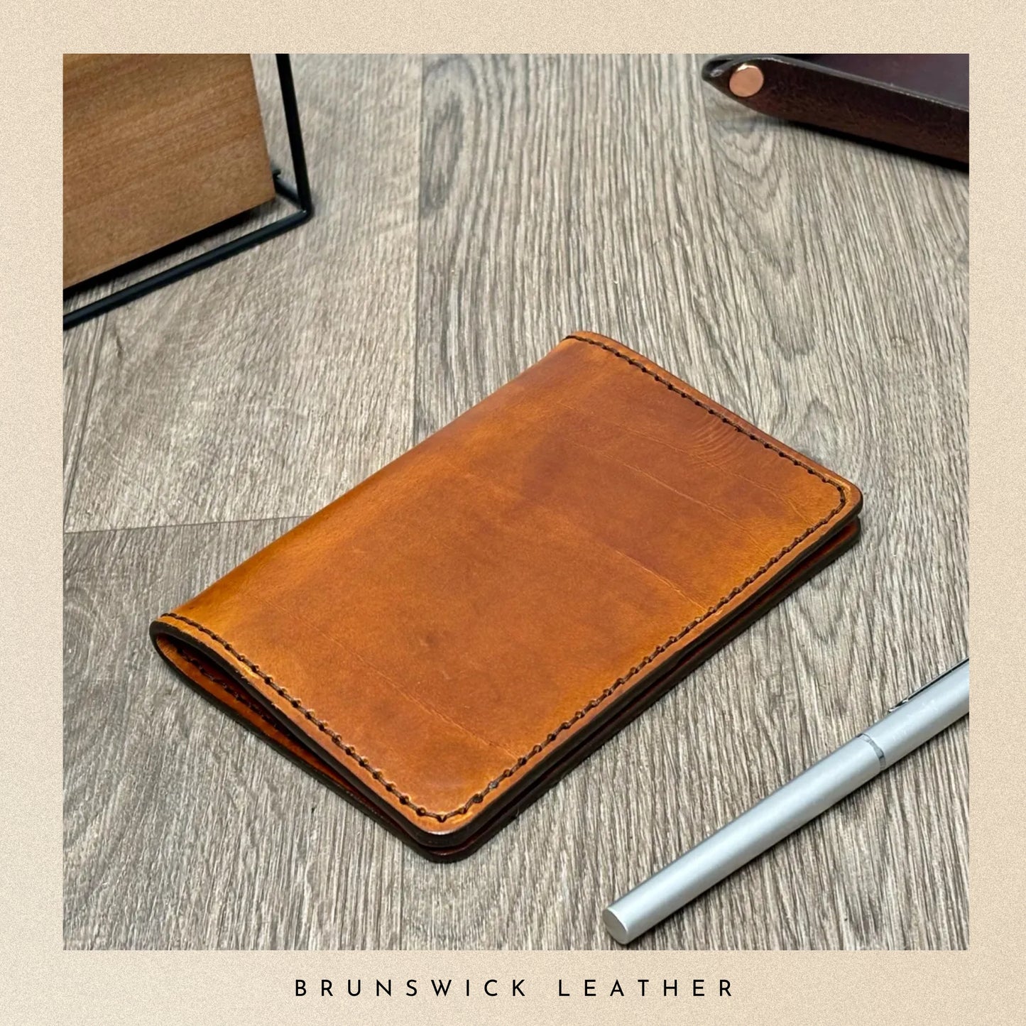 Brown leather wallet on a wooden surface with 'Brunswick Leather' branding.