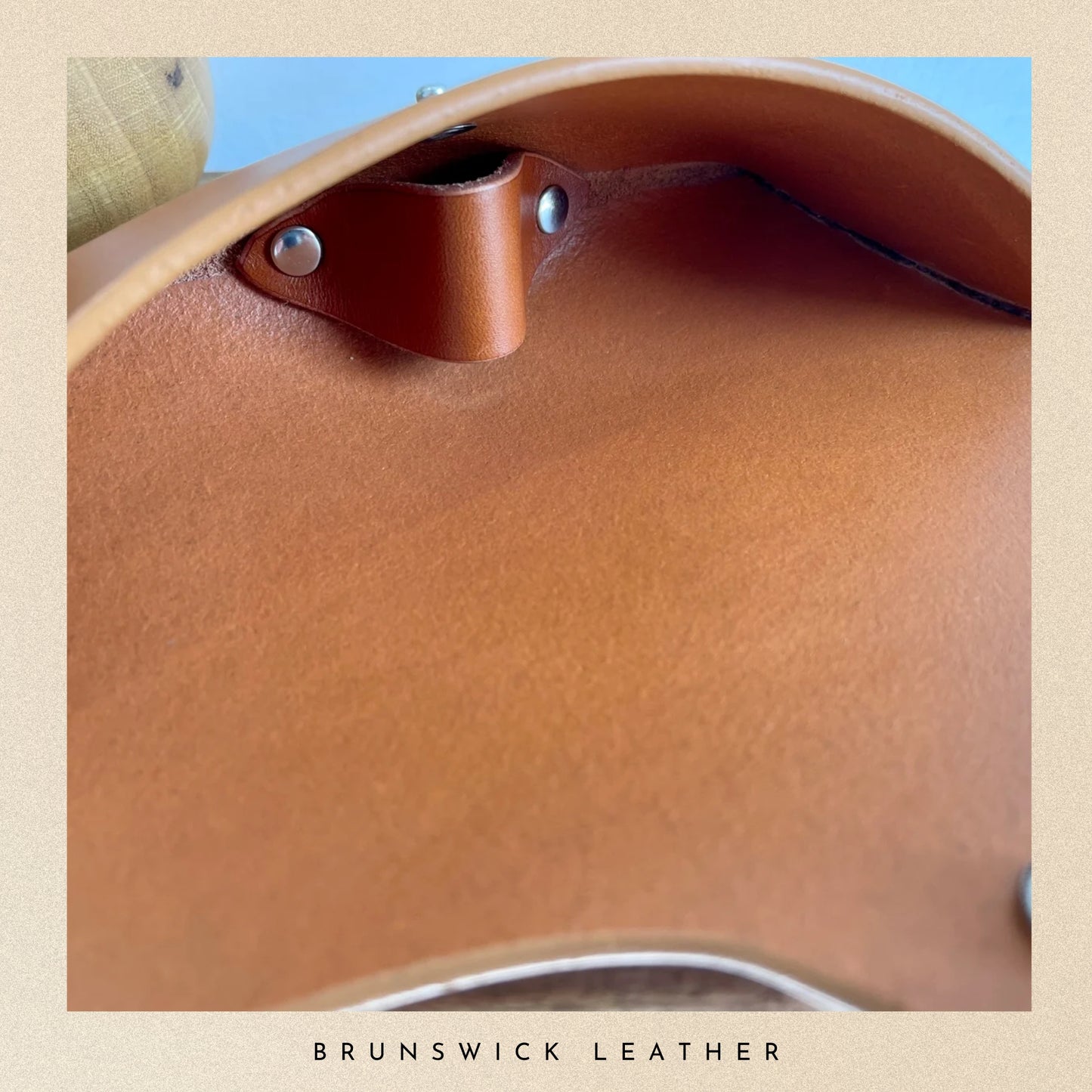 Close-up of a brown leather saddle with 'Brunswick Leather' branding.