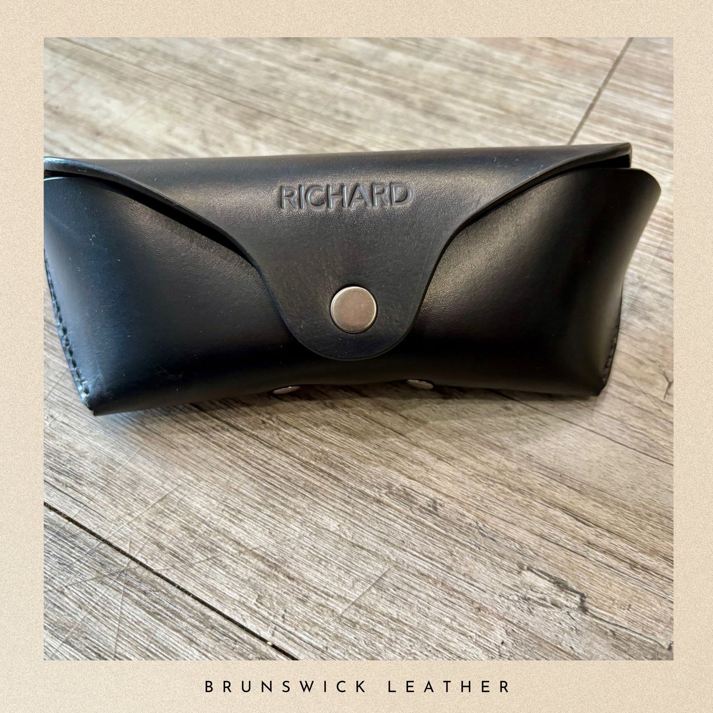 Black leather case with 'Richard' branding on a wooden surface, featuring 'Brunswick Leather' text.